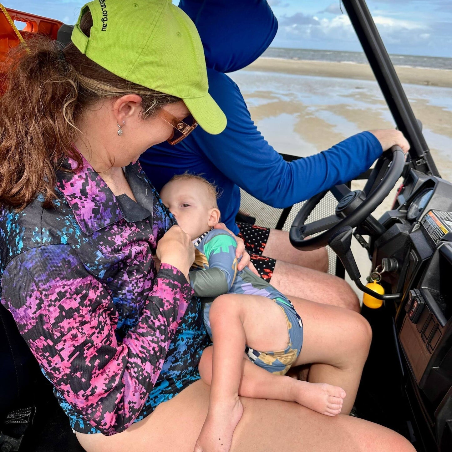 Woman breastfeeding baby in breastfeeding fishing shirt while in buggy on the beach