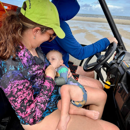 Woman breastfeeding baby in breastfeeding fishing shirt while in buggy on the beach